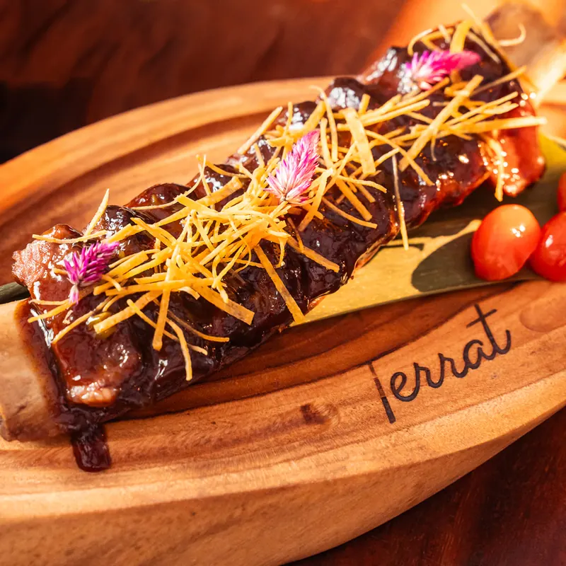 Costillas glaseadas servidas sobre tabla de madera con el logo de Terrat