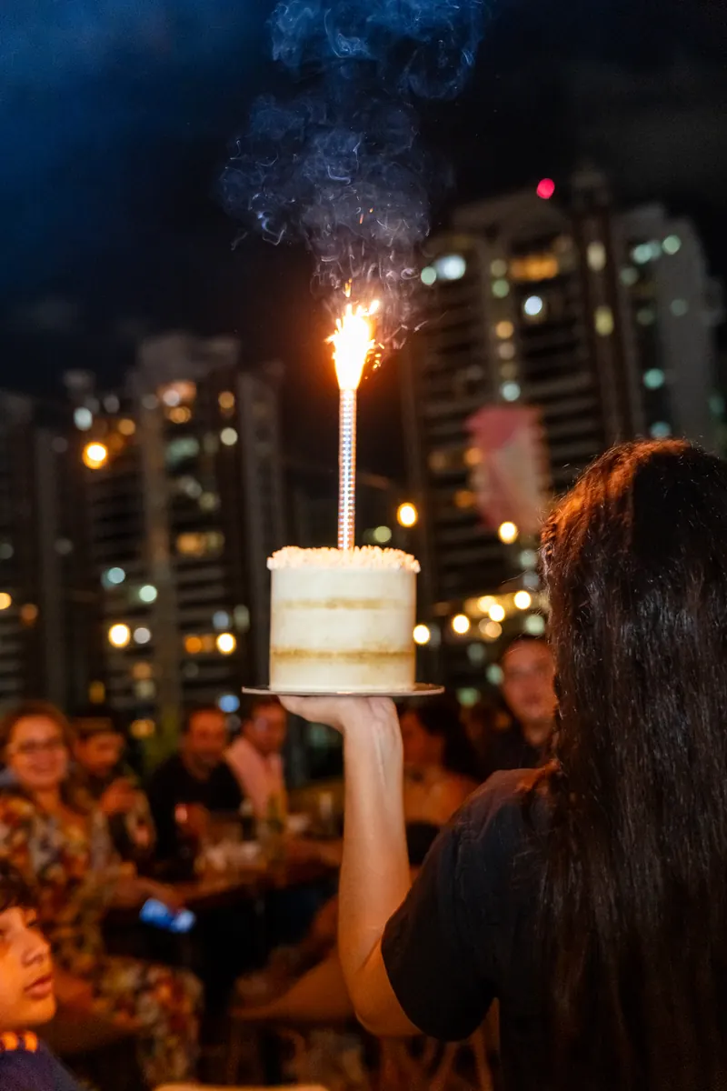 Pastel de cumpleaños con bengala y la ciudad de noche en Terrat